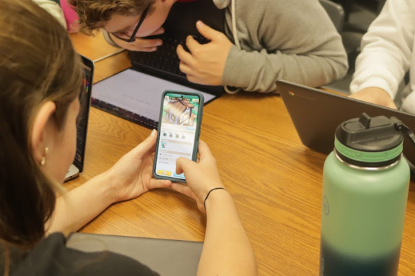 Student on their phone, bonding with classmates. 